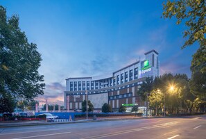 A Holiday Inn Express hotel with a modern architectural design, located near a road with a clear sky. - Holiday Inn Express Shanghai Jiading Center by IHG (Shanghai)
