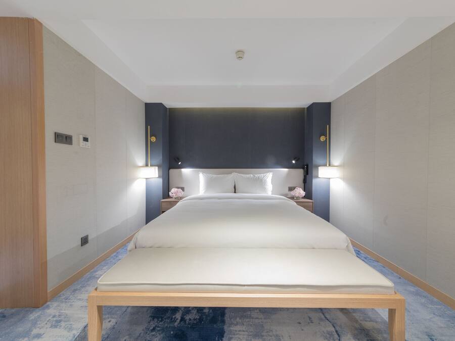 Una habitación de hotel moderna con una cama grande, lámparas de noche y suelo de madera.