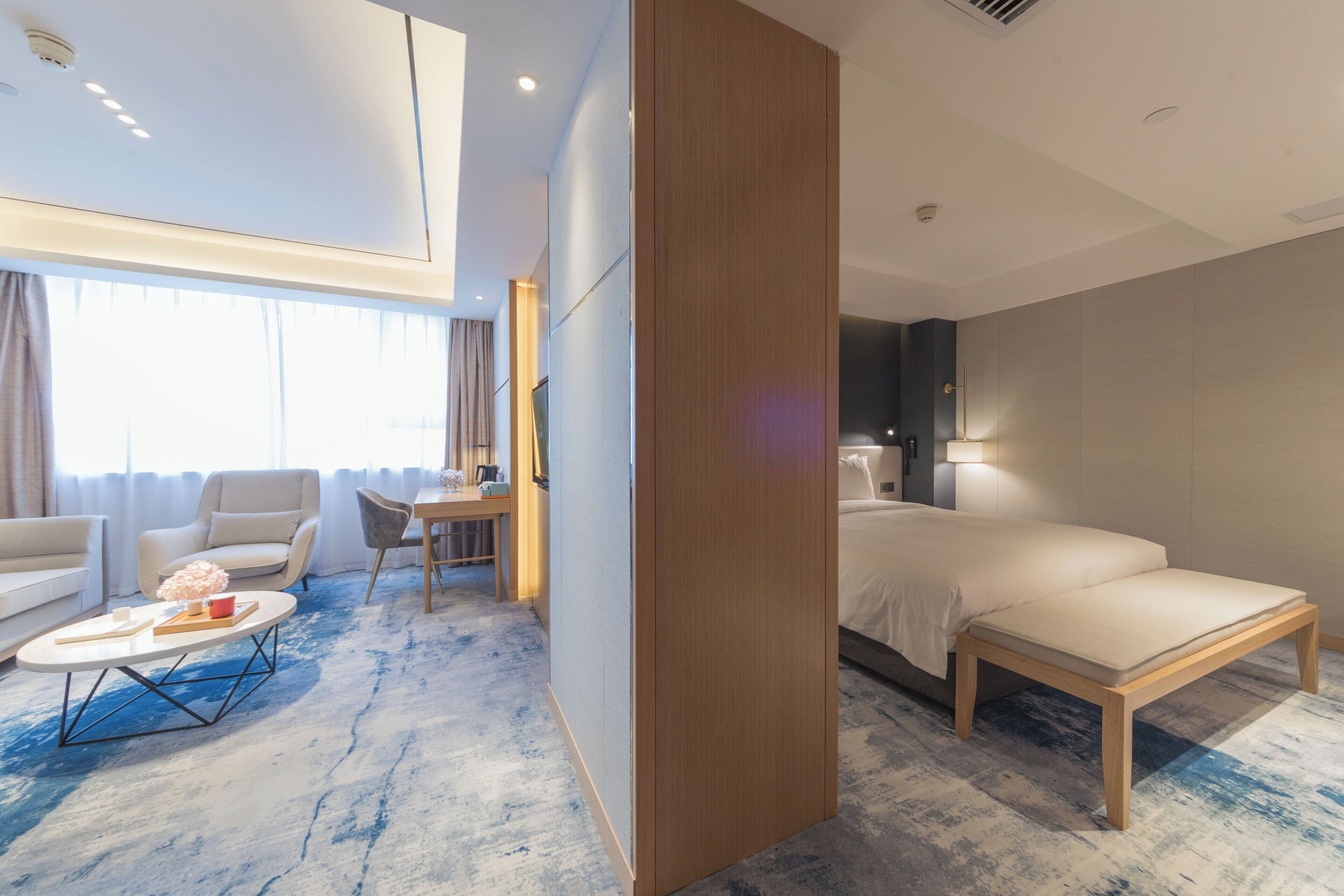 A hotel room with a bed, a sofa, a coffee table, and a desk.