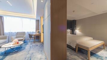 A hotel room with a bed, a sofa, a coffee table, and a desk.
