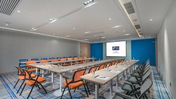 A conference room with a long table, multiple chairs, and a projector screen displaying a presentation.