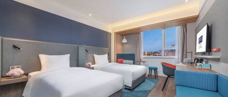 Habitación de hotel con dos camas, un sofá, televisión y vistas a la ciudad.