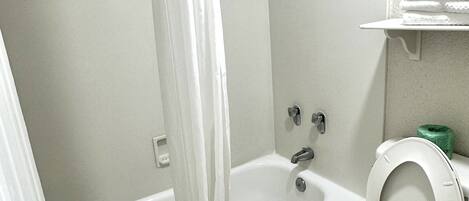A bathroom with a bathtub, toilet, and shower curtain.