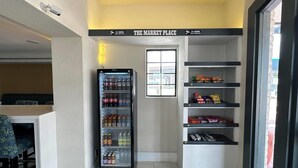 A compact room with a vending machine stocked with beverages, a small seating area, and shelves with snacks. - Baymont by Wyndham Nacogdoches Near University (Nacogdoches)