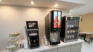 A coffee station with a coffee machine, a refrigerated display case, and a tray with cups and a bottle. - Baymont by Wyndham Nacogdoches Near University (Nacogdoches)
