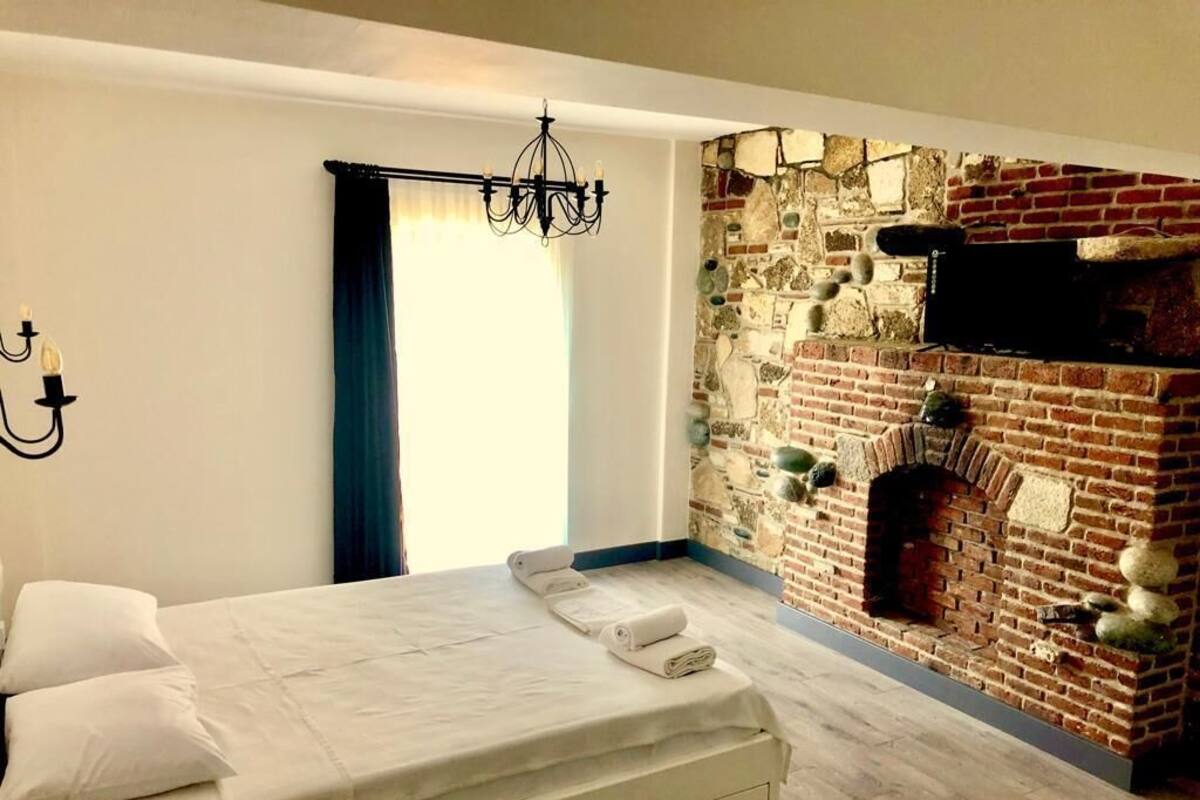 A bedroom with a bed, a brick wall, and a fireplace.