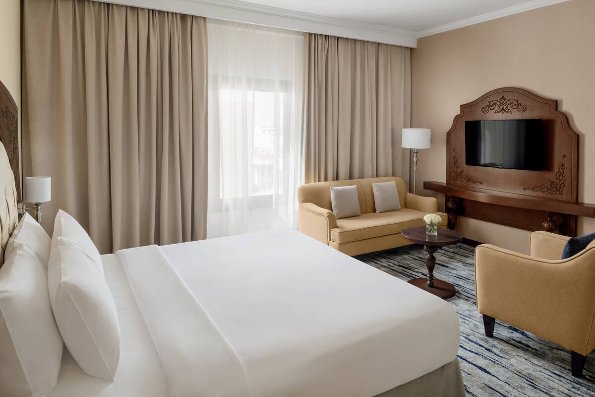 A hotel room with a bed, a sofa, a TV, and a desk.