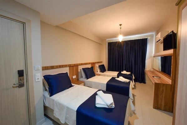 A hotel room with two beds, a wooden headboard, a flat-screen TV, and a ceiling light.