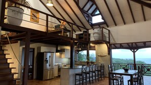 A spacious kitchen with a central island, a dining area with outdoor seating, and a view of the landscape. - Between luxury and authenticity.  Beautiful sea view property, 100m from the beach. (Deshaies)