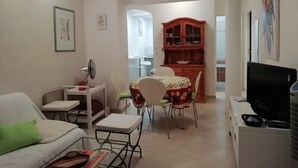 A compact living space with a sofa, a dining table with chairs, a small kitchen area, and a television. - BEAUTIFUL 2 BEDROOM APARTMENT WITH TERRACE 50 M BEACH WIFI (CAVALAIRE sur mer)