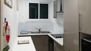A compact kitchen with a window, a sink, a stove, and a microwave. - BEAUTIFUL 2 BEDROOM APARTMENT WITH TERRACE 50 M BEACH WIFI (CAVALAIRE sur mer)