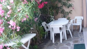 A patio area with a white table and chairs, surrounded by pink flowering plants. - BEAUTIFUL 2 BEDROOM APARTMENT WITH TERRACE 50 M BEACH WIFI (CAVALAIRE sur mer)