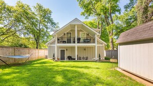 Ein zweistöckiges Haus mit überdachter Veranda, umzäuntem Garten und Trampolin.
