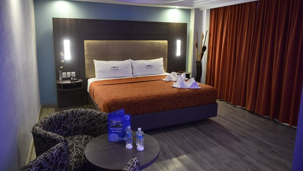 Una habitación de hotel con una cama grande, una mesa redonda con un menú y una mesita de noche con una lámpara.