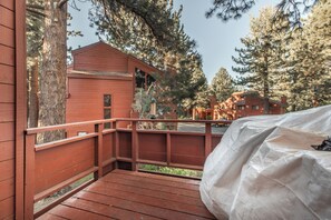 A wooden deck with a covered area, overlooking a forested area with multiple cabins. - Townhouse Art Gallery in Mammoth's Best Location (Mammoth Lakes)
