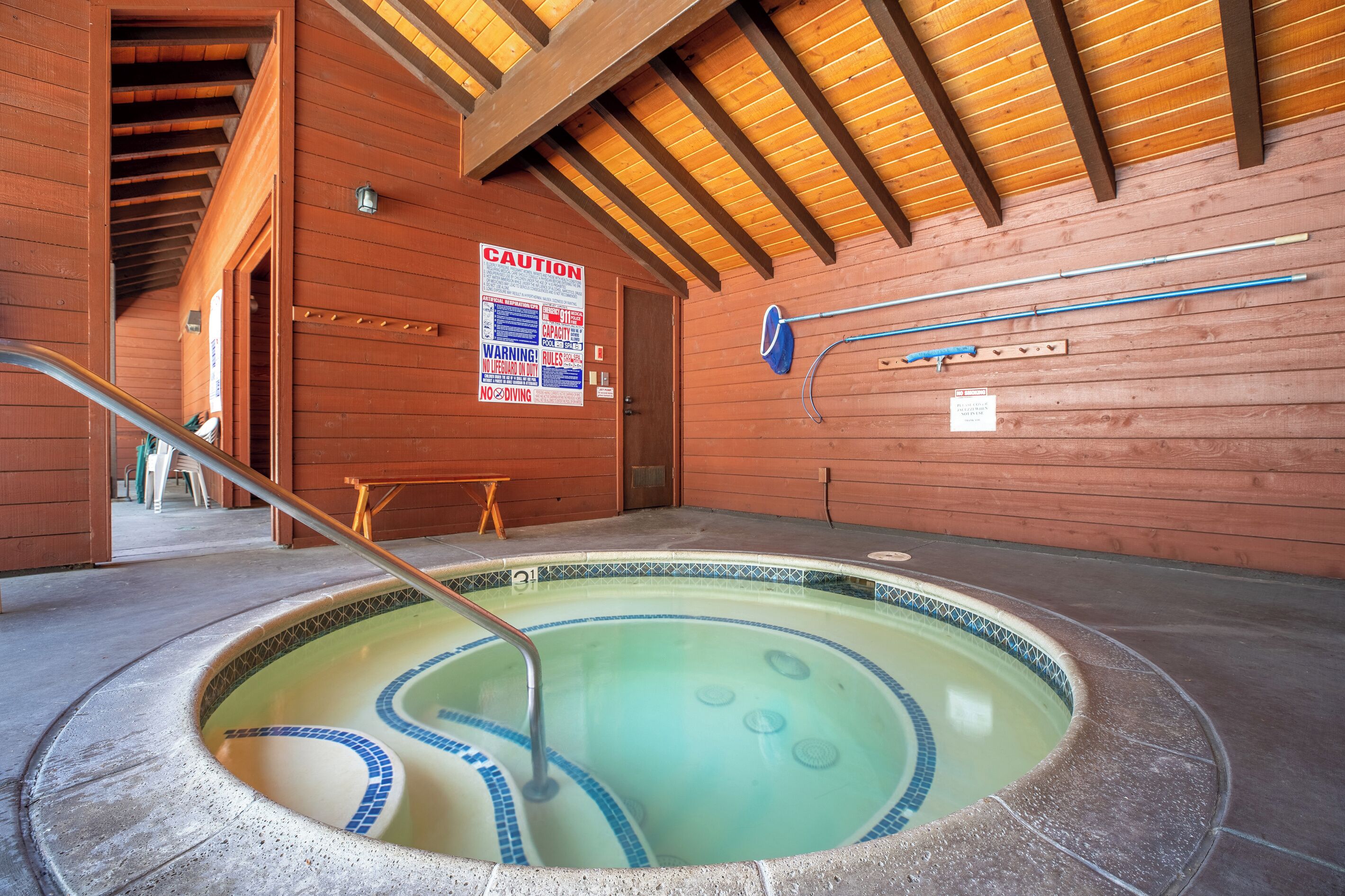 Un bain à remous avec un intérieur en bois, un panneau d’avertissement et un escalier pour piscine.