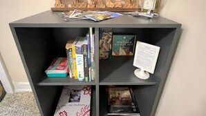 Une bibliothèque remplie de livres, une bouteille de vin et un verre.