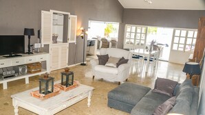 A spacious living room with a white sofa, grey couch, and a dining area with a table and chairs. - Hakuna Matata Bonaire (Kralendijk)