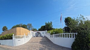 Ein verschlossenes Tor mit hölzerner Struktur, weißen Mauern und einer Fahnenstange.