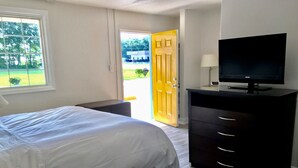 Un dormitorio con cama, cómoda, televisión y ventana con vistas al exterior.