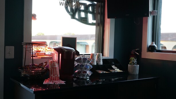 Una barra con una máquina de café, un cuenco de aperitivos y una bandeja de tazas.