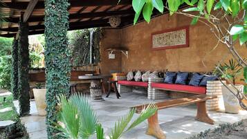 Un área de estar al aire libre con un banco de madera, una mesa y un banco acolchado con almohadones.