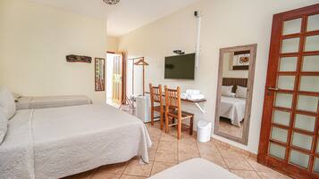 Habitación de hotel con dos camas, televisor, espejo y una silla de madera.