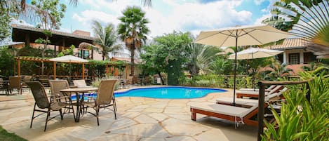 A pool area with lounge chairs, a table, and umbrellas.