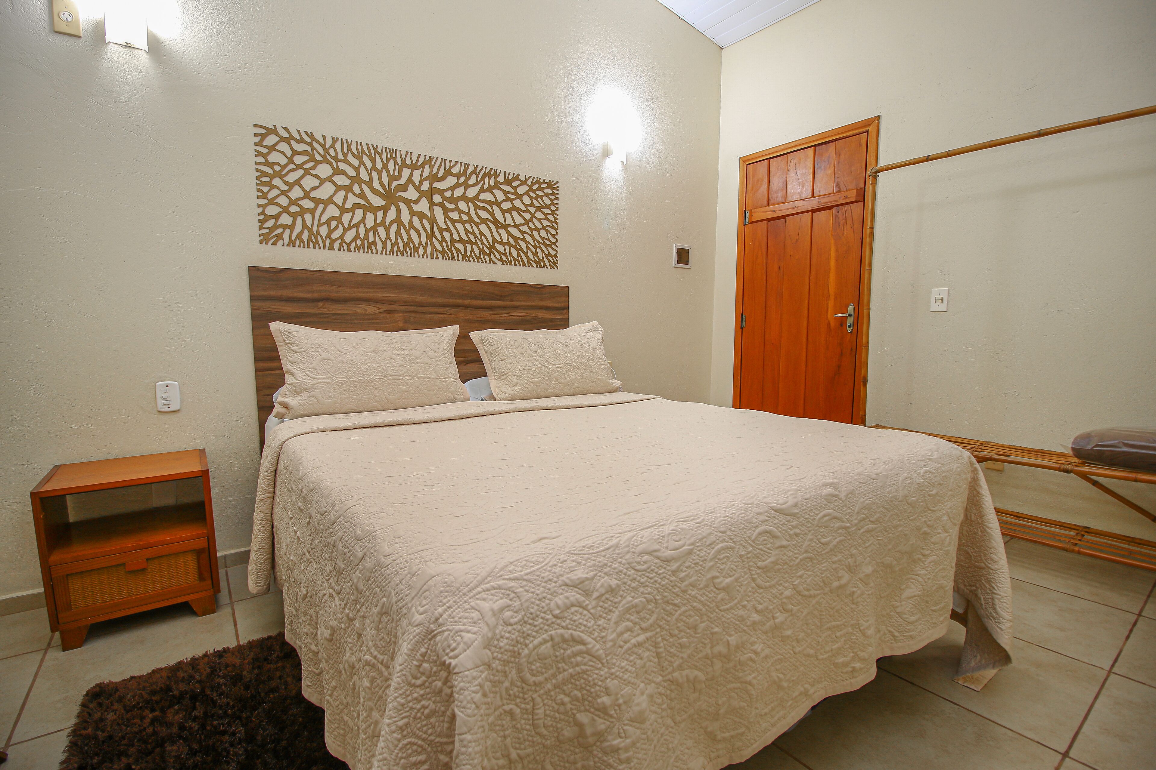 Un dormitorio con cama, mesita de noche, armario y un adorno en la pared.