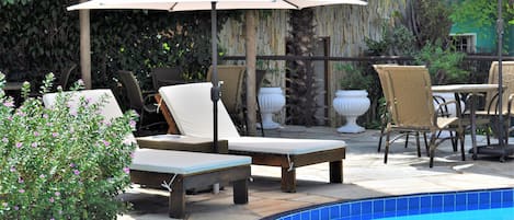 Una piscina al aire libre, sillones reclinables de piscina