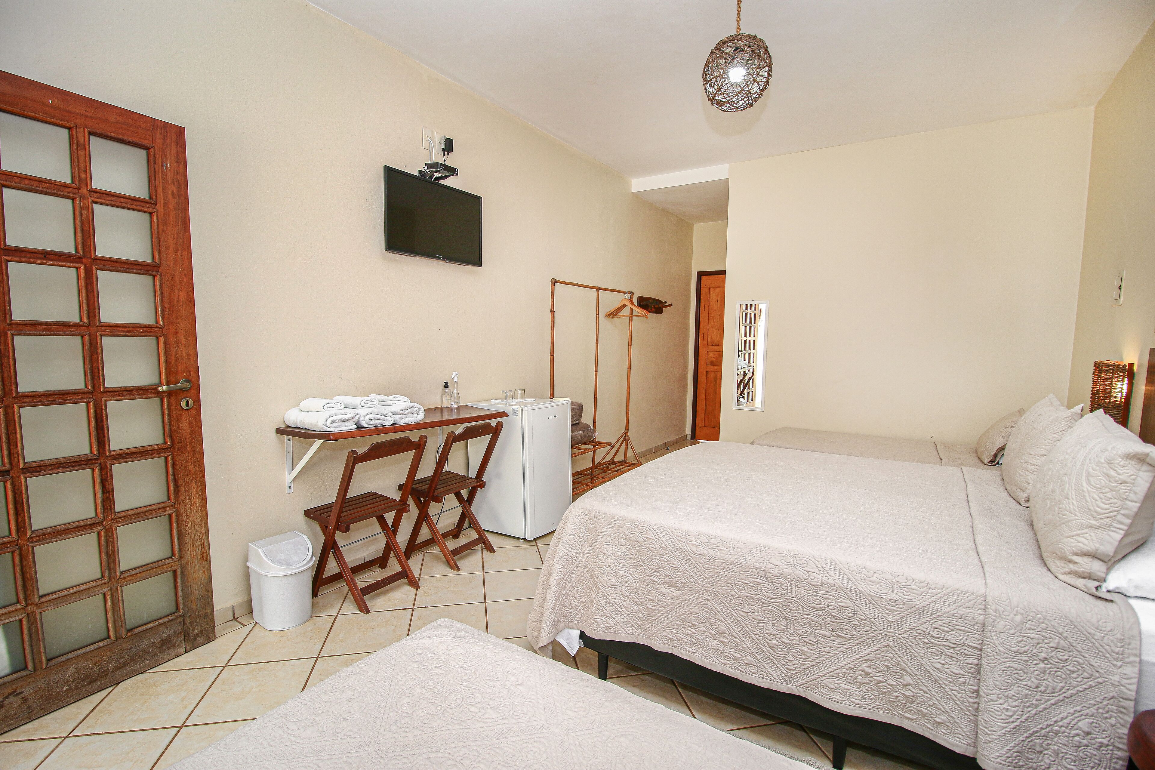 A hotel room with two beds, a desk with a chair, a TV, and a wardrobe.