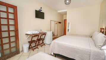 A hotel room with two beds, a desk with a chair, a TV, and a wardrobe.