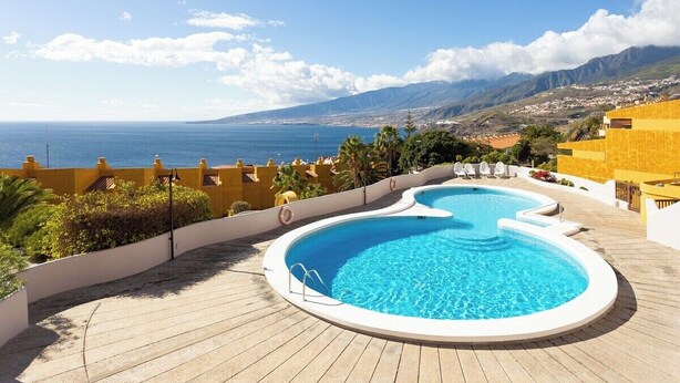 Ein Pool auf dem Dach mit freiem Blick auf das Meer und die dahinterliegenden Berge.