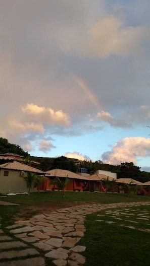 A residential area with houses, a stone pathway, and a rainbow in the sky.
