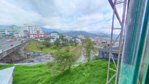 Vista desde una ventana sobre un paisaje urbano con un puente, edificios y zonas verdes.