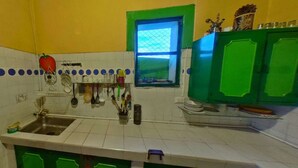Una cocina con azulejos blancos, un lavamanos y armarios verdes.