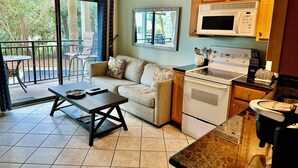 A compact kitchen with a dining area, a sofa, and a view of the outdoors. - SeaClusion-Oceanview, Mini split AC, Beach Chairs (Hilton Head Island)