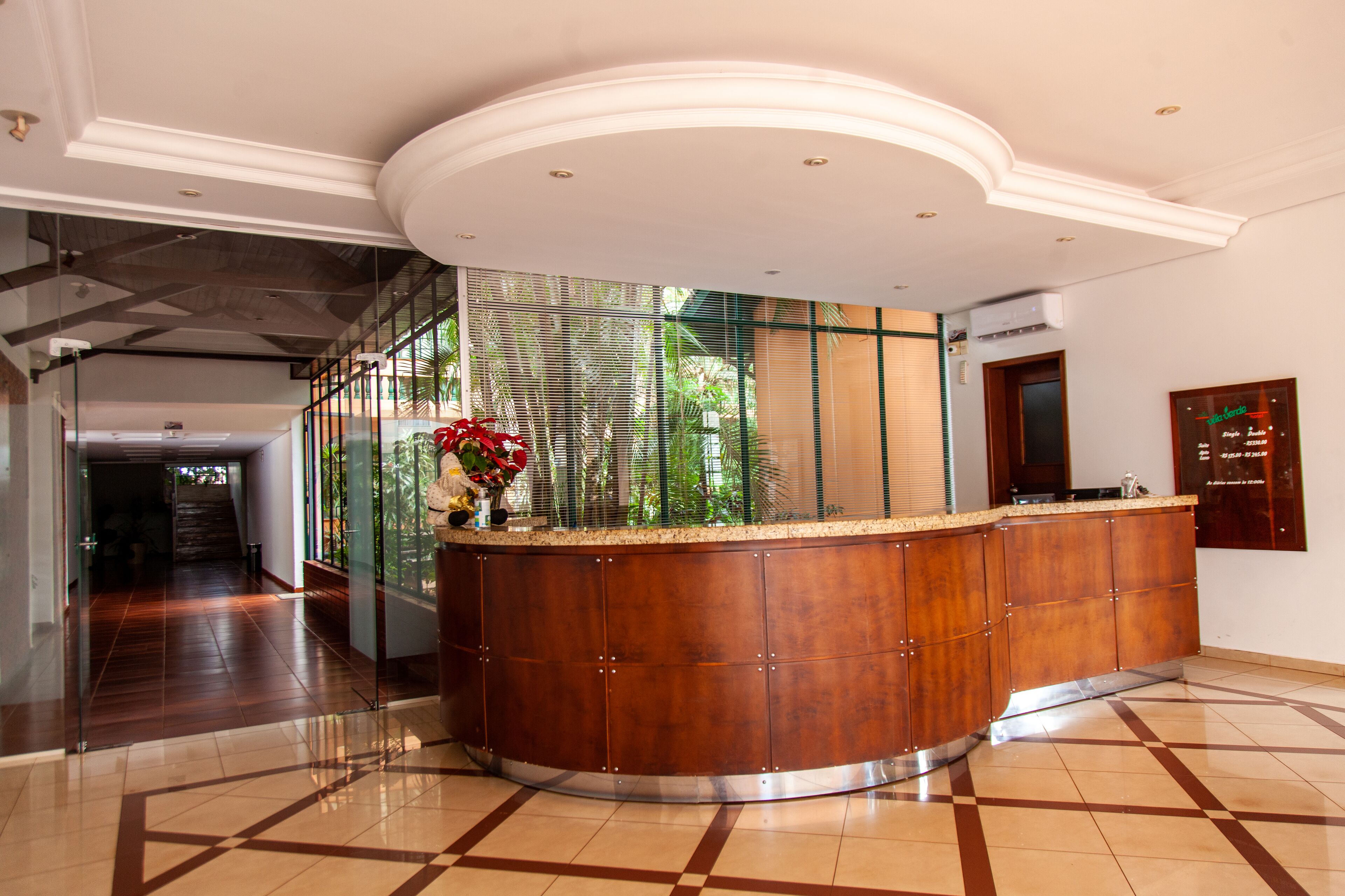A reception area with a curved wooden counter, glass doors leading to a hallway, and a tiled floor with a geometric pattern.
