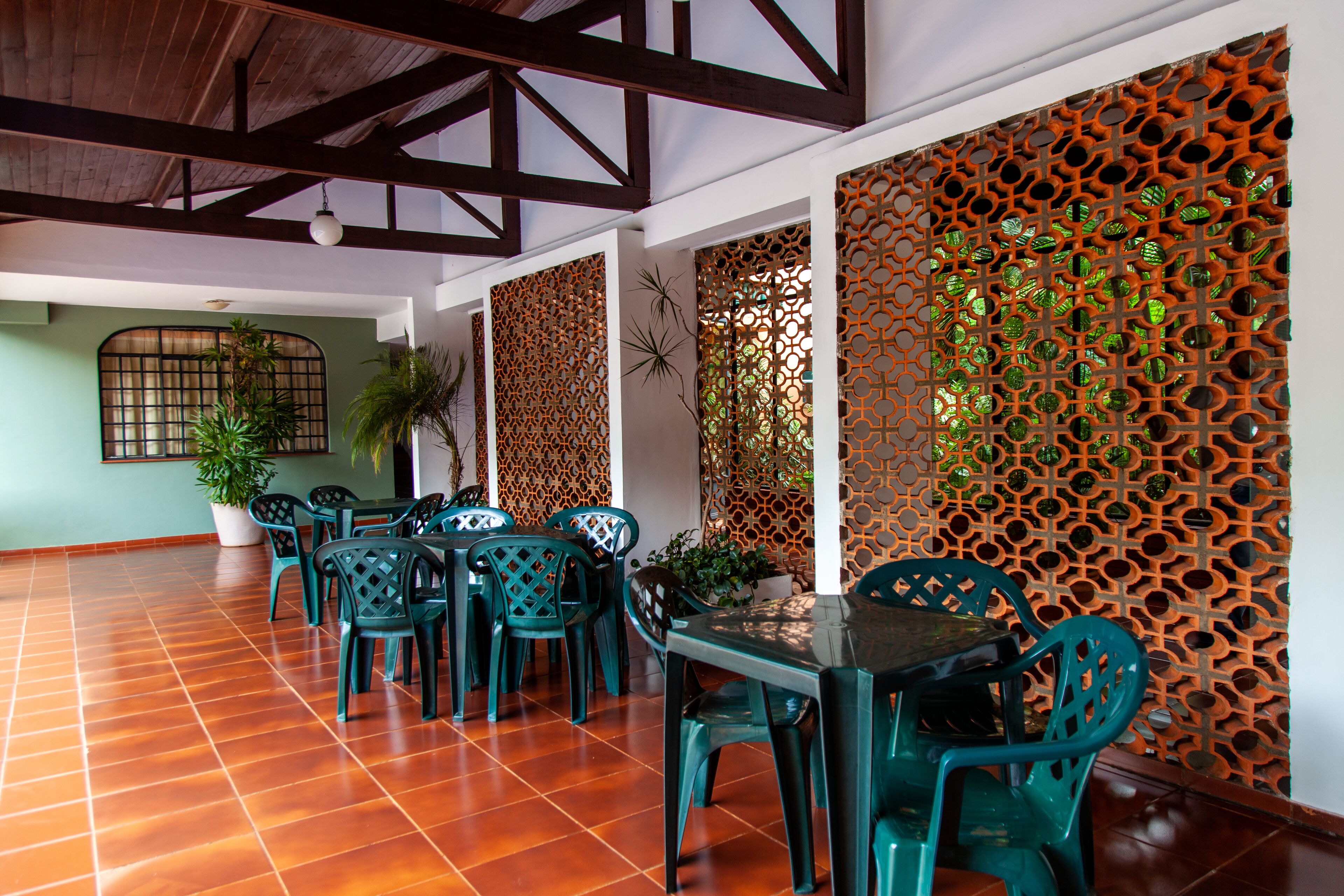A dining area with a wooden ceiling, green plastic chairs, and a patterned wall.