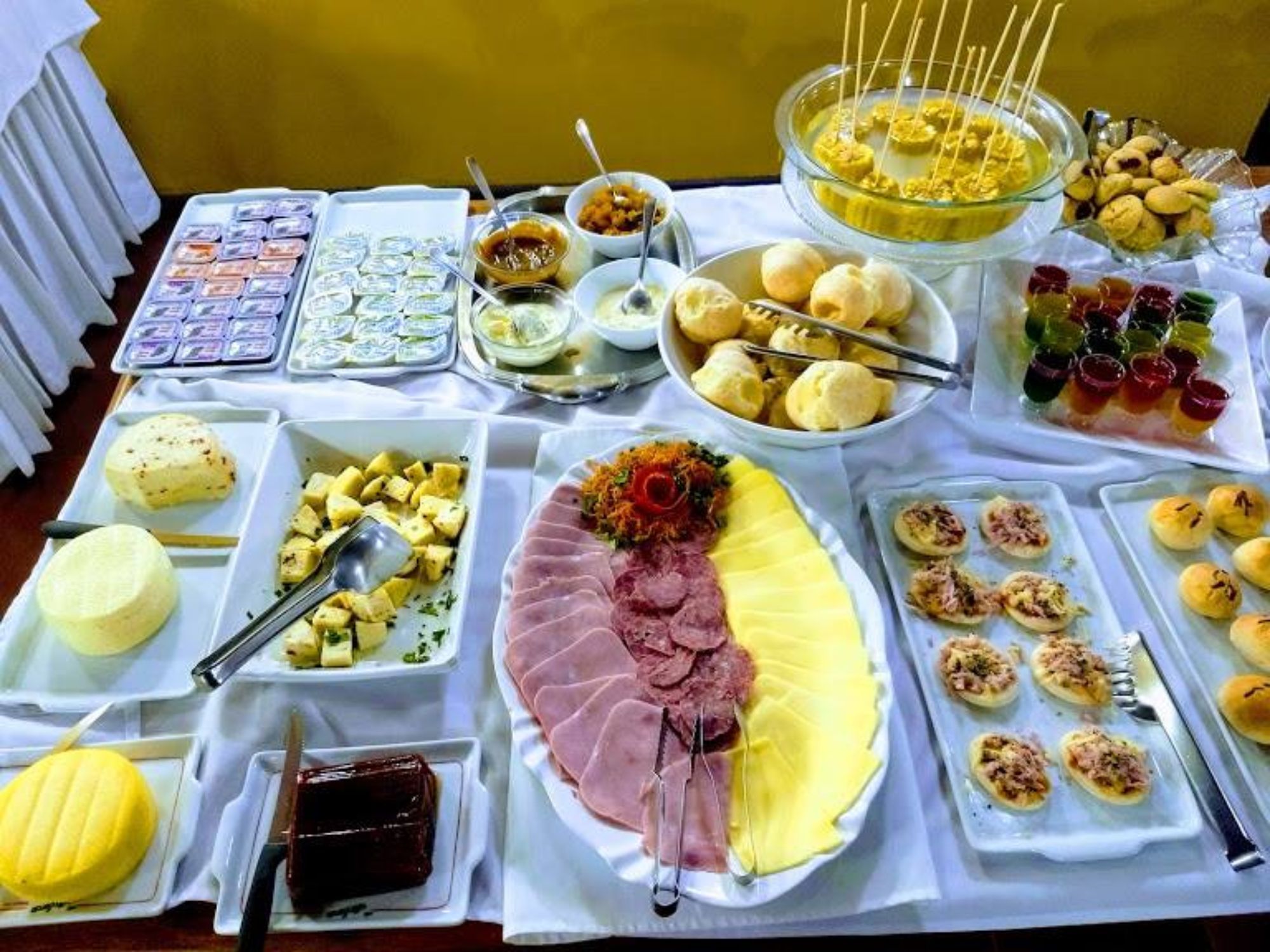 A buffet with various dishes including meats, cheeses, and desserts.