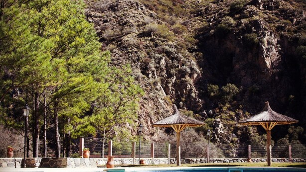 A swimming pool with a mountain backdrop, surrounded by trees and a gazebo. - Paso del Cóndor (Nogolí)