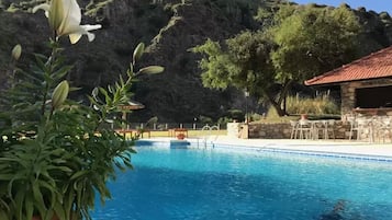 Una piscina al aire libre de temporada, sombrillas