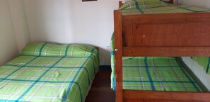 A small, single-bed room with a plaid bedspread and a wooden bunk bed. - Finca Hotel El Barranco (Montenegro)