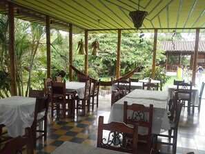 A covered outdoor dining area with tables and chairs, surrounded by lush greenery. - Finca Hotel El Barranco (Montenegro)