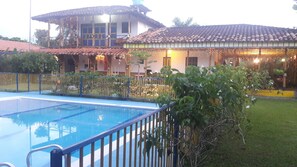 A swimming pool with a blue deck, surrounded by a fenced area with greenery. - Finca Hotel El Barranco (Montenegro)