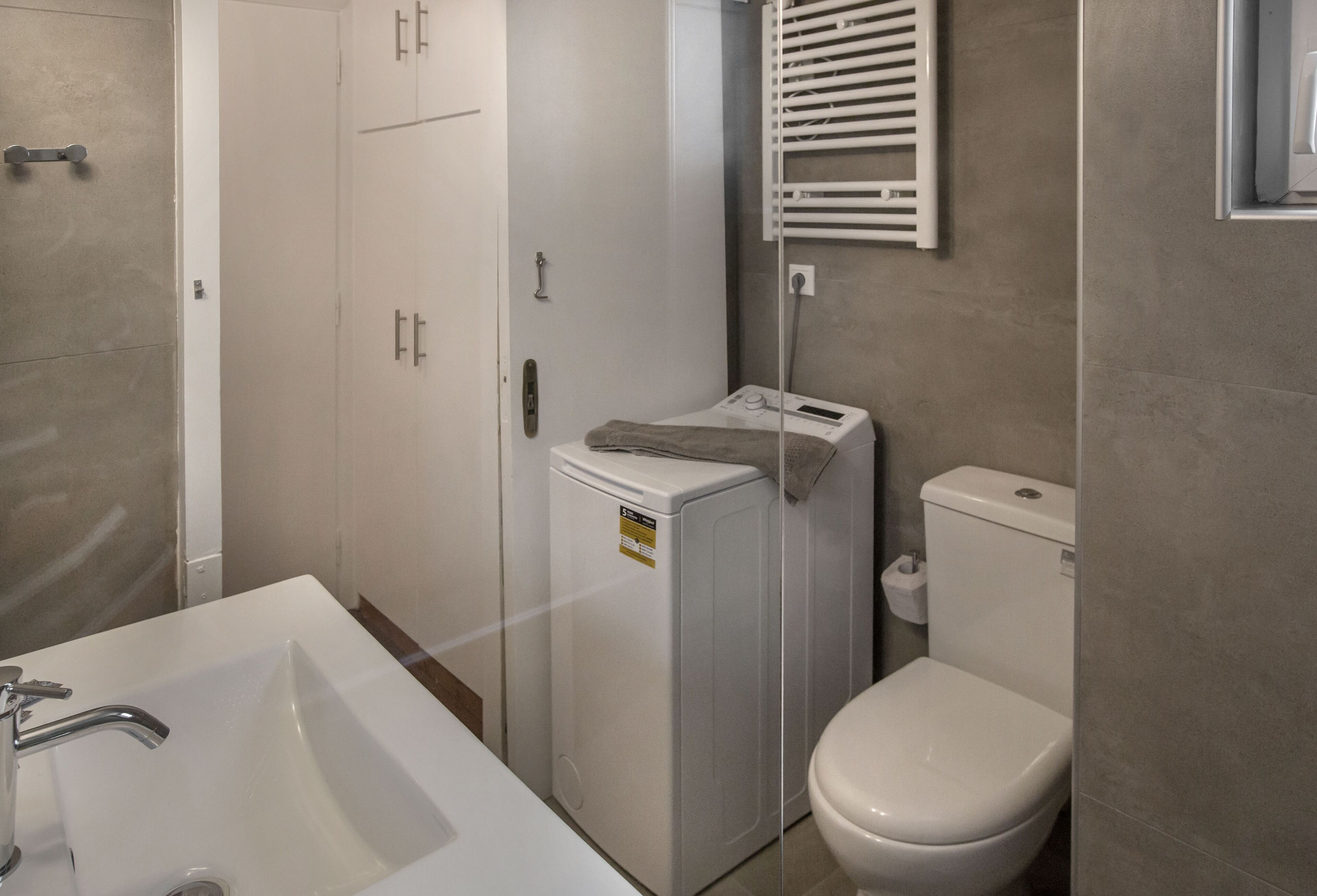 A bathroom with a white sink, a washing machine, and a toilet.