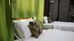 Habitación de hotel con dos camas, cada una con ropa blanca y almohadones decorativos.