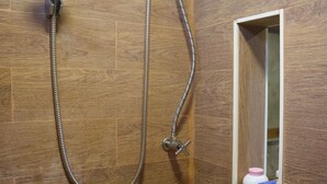Una ducha con cabezal de ducha de mano y panel de control en la pared.