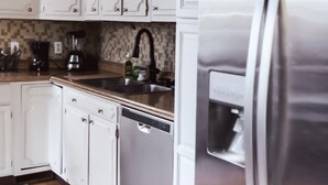 A modern kitchen with white cabinets, a stainless steel refrigerator, and a dishwasher. - The Eureka: Four King Bedroom House (Champaign)