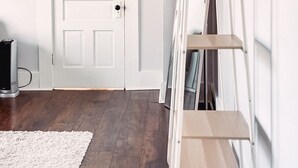 A hallway with a white door, a white radiator, and a wooden floor. - The Eureka: Four King Bedroom House (Champaign)